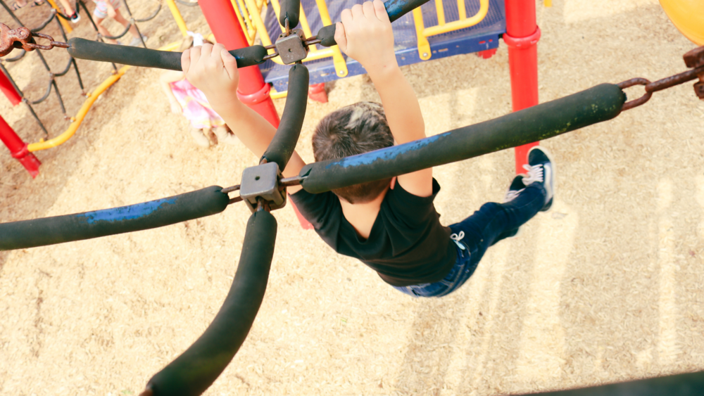Boy swings from obstacle on playground